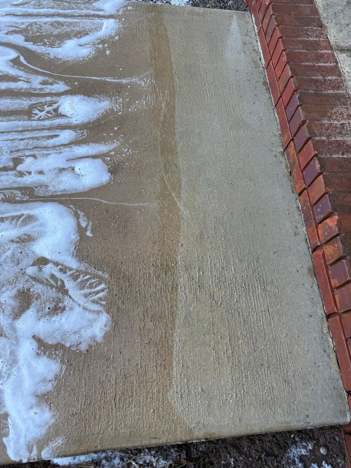 Concrete sidewalk mid clean showing foam and cleaning progress